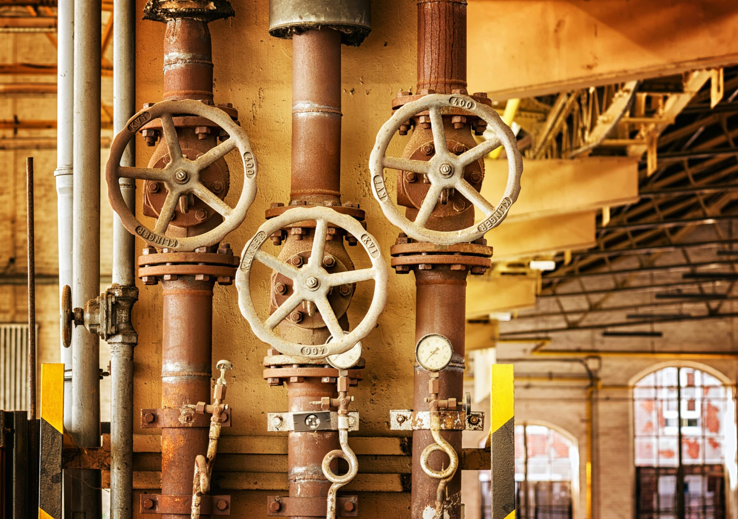 pexels-photo-357440-357440 Close-up of rusty industrial pipes and valves, showcasing aging machinery in a factory setting.